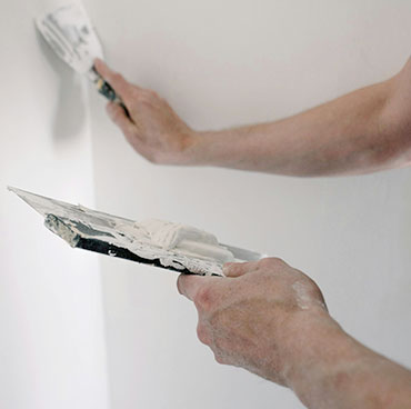 A man filling a hole by drywall & plaster repair in Oshawa